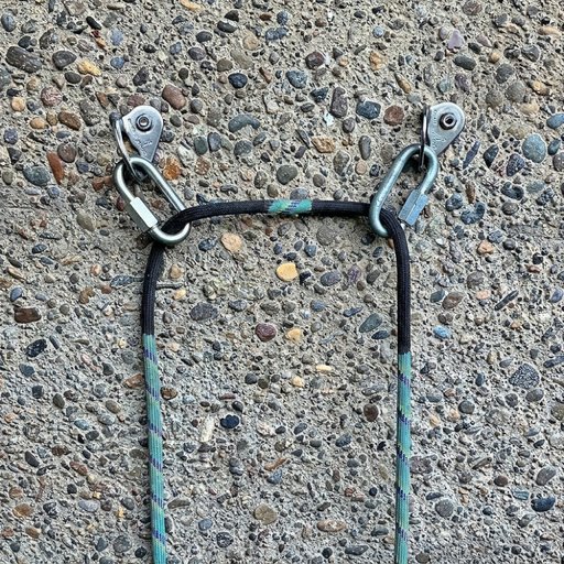 Two bolts on a wall, each with a quick link hanging from its hanger. The rope runs through both
                  quick links, which sit at an angle to the rope.